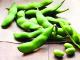 Shelled edamame on a wood background with a few shelled beans