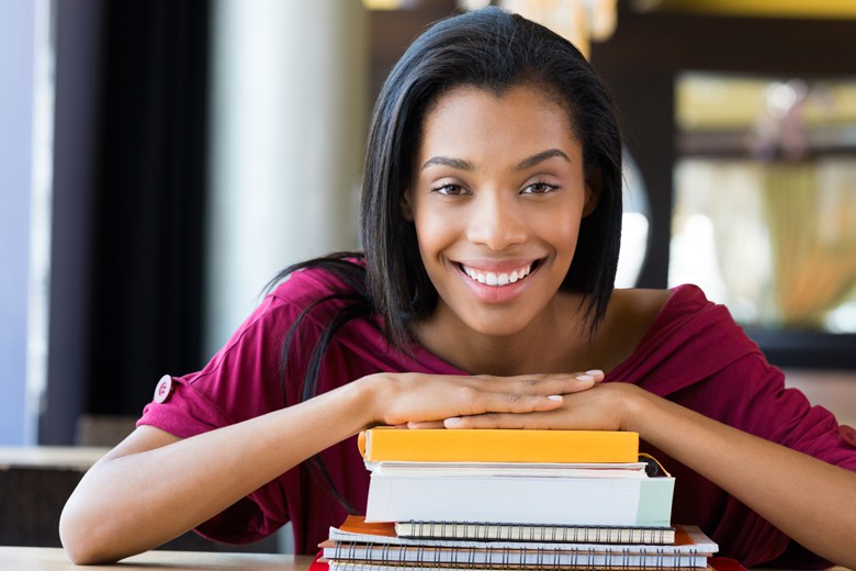 Student girl leans on stack of books