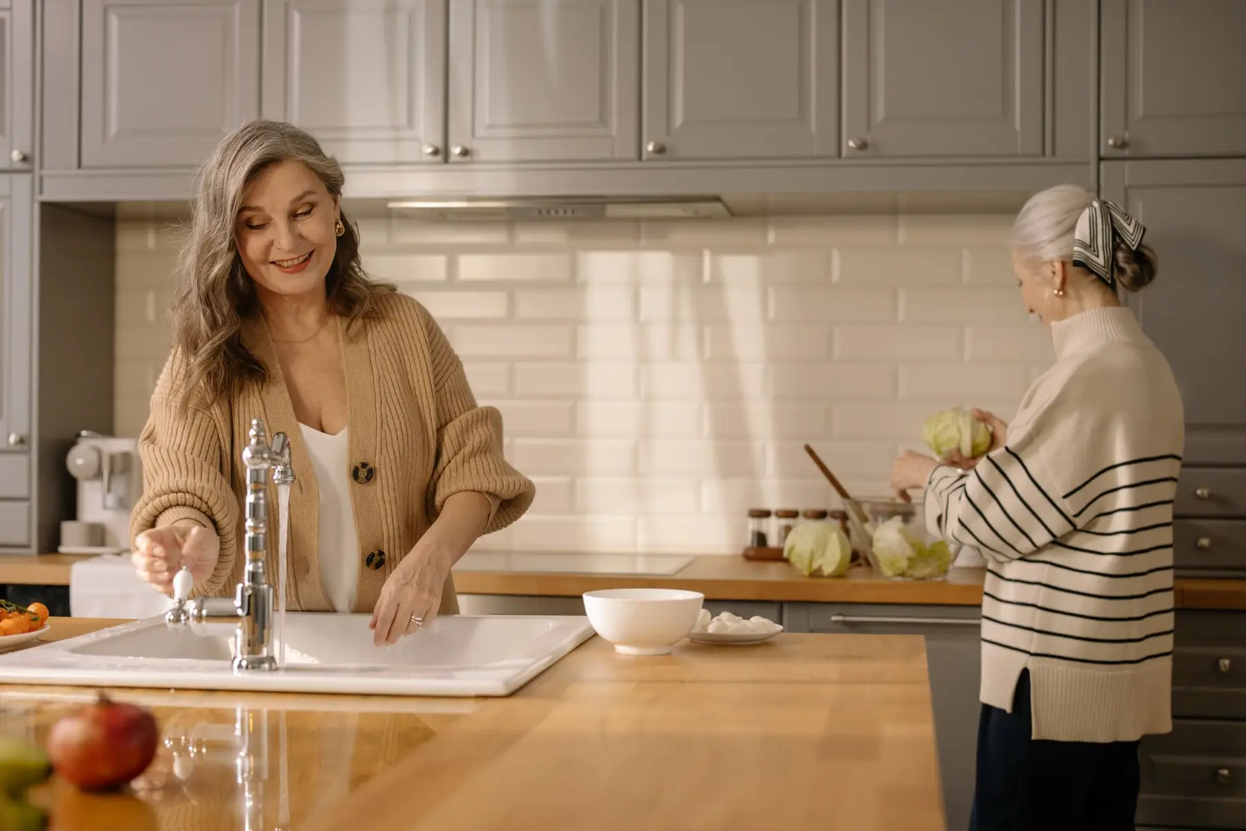 Two senior women smiling and spending time together in a cozy kitchen