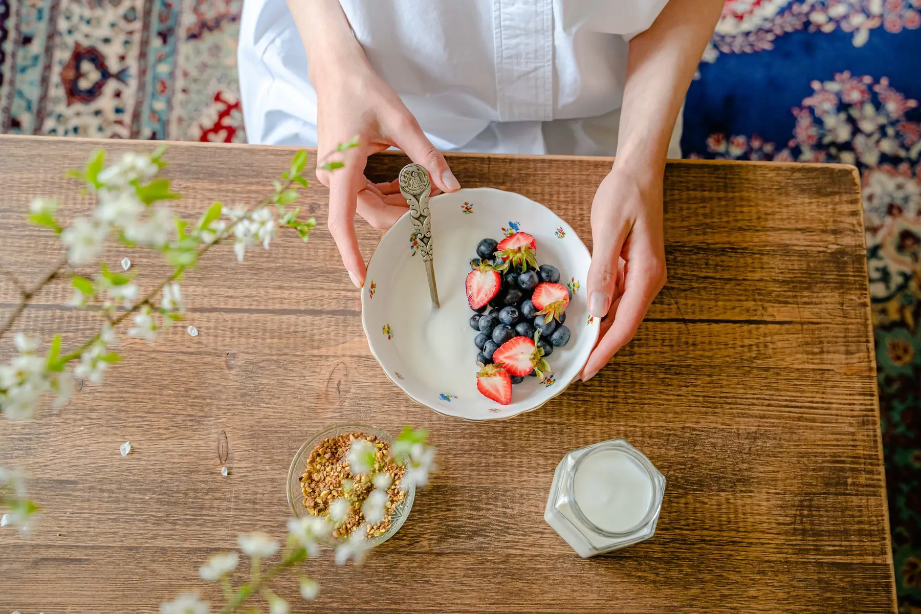 A top view of a person preparing a healthy breakfast with fresh berries, milk,