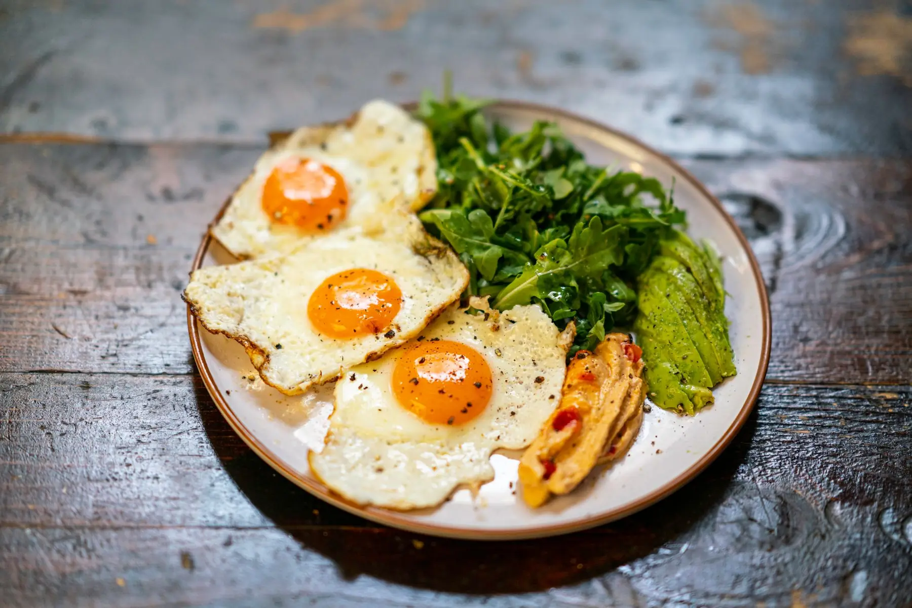 Delicious breakfast plate of fried eggs, arugula salad, and veggies