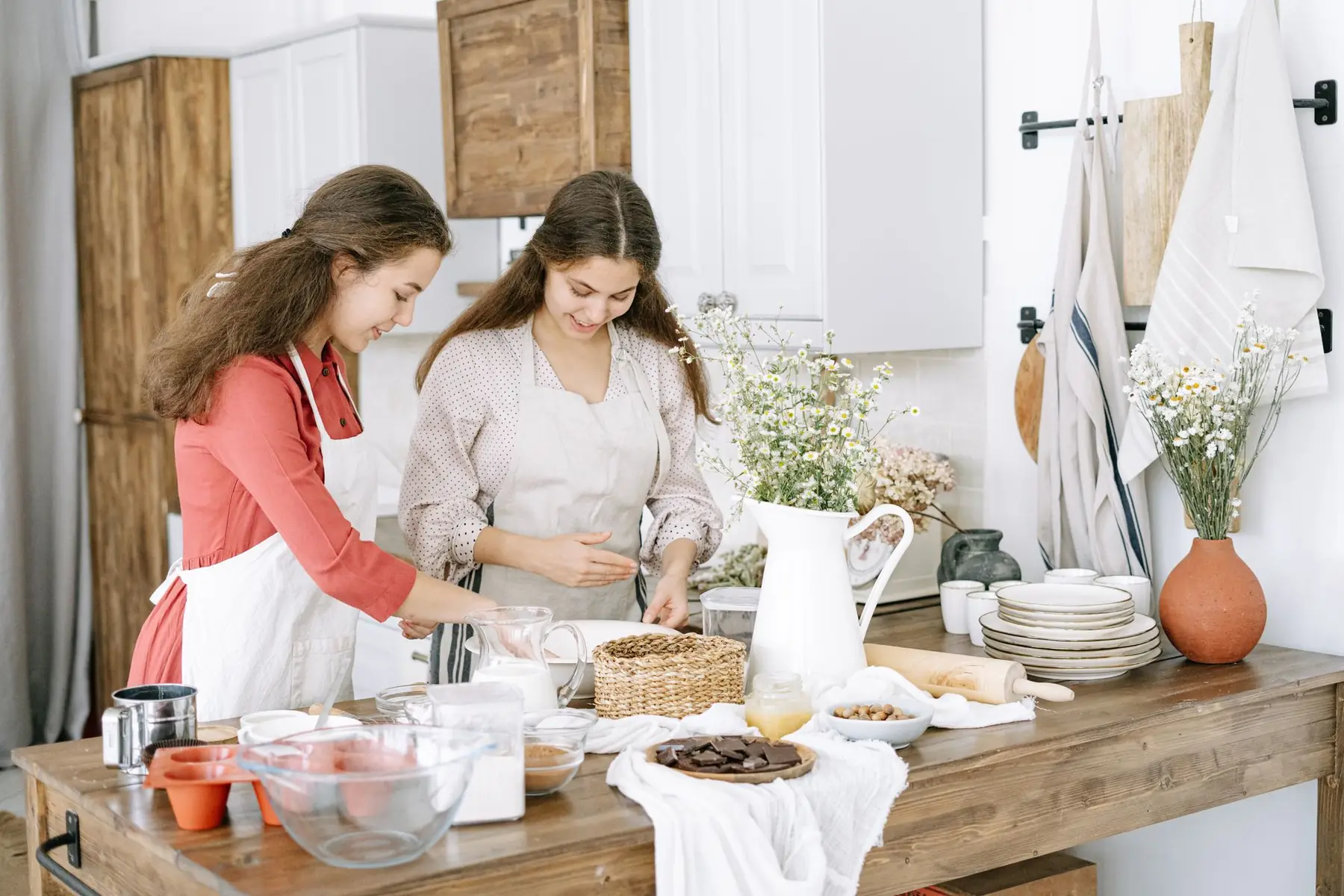 Two young women happily baking together in a cozy home kitchen setting
